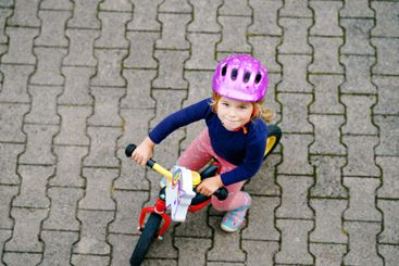 Little toddler girl running with balance bike on summer...
