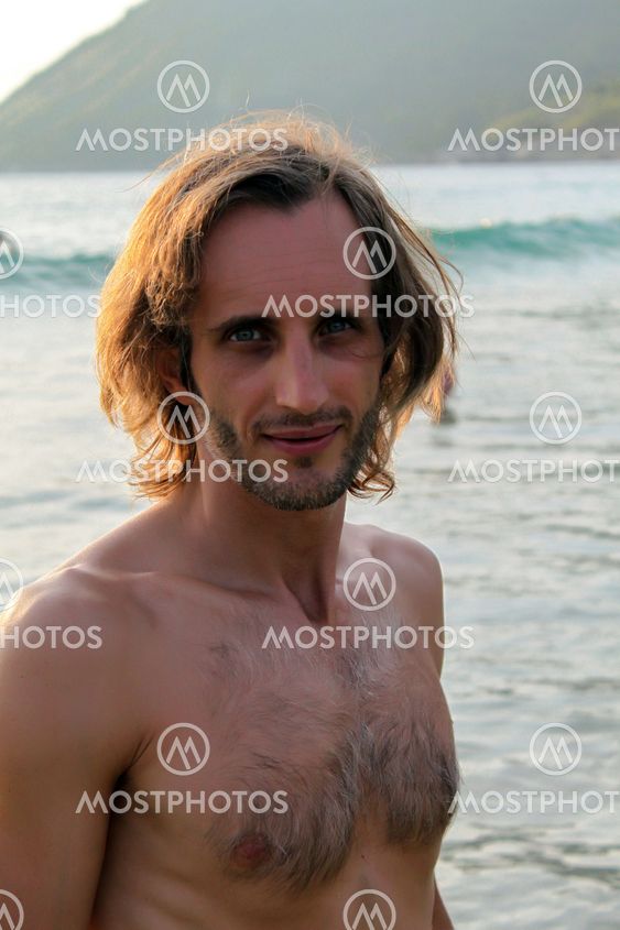 colorfull portrait of handsome man looking up and smiling during day at the beach.