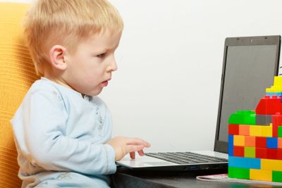 Happy childhood. Boy child kid playing on laptop. At home.