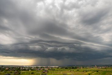 Moody landscape with dark stormy clouds with falling...