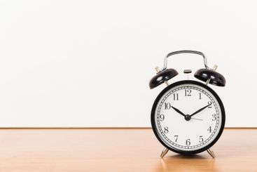 Black vintage alarm clock on wooden table