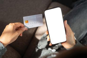 Top view of a woman sits indoors, holding a credit card...