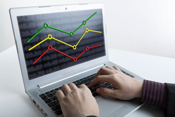 hands of a person working on a computer with graphs