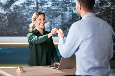 Man At Hotel Talking To Receptionist Woman