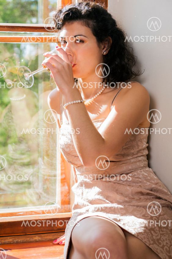 Woman drinking wine from glass on sill
