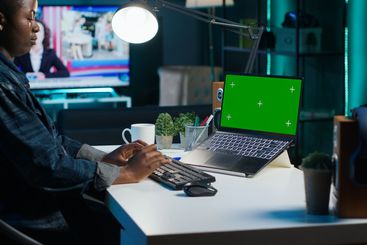 Woman arriving in home office, sitting down at desk,...