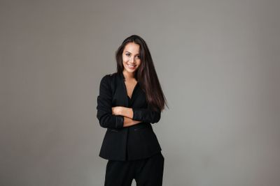 Smiling brunette woman in black suit standing with arms...