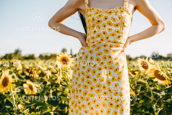 Young caucasian woman in sunflower dress standing in...
