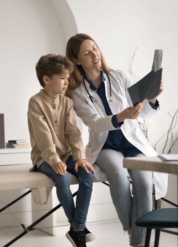 Little boy patient look on radiographs in female doctor...