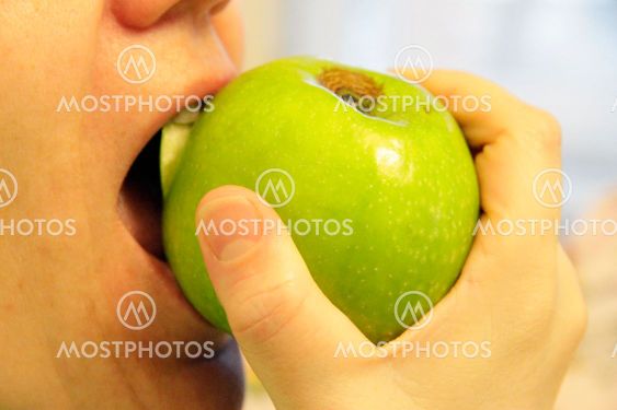 Woman bit a green apple isolated on the white
