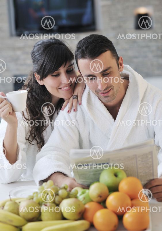 Happy couple reading the newspaper in the kitchen at breakfast