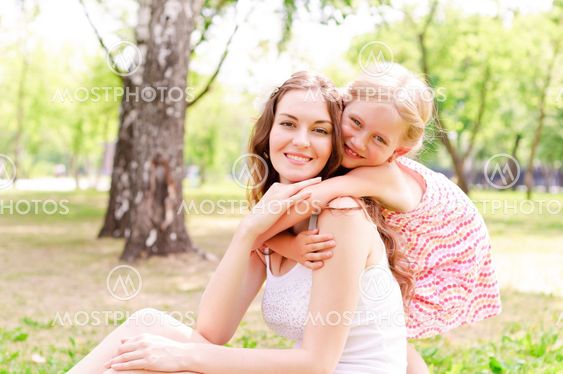 mother and daughter sitting together on the grass