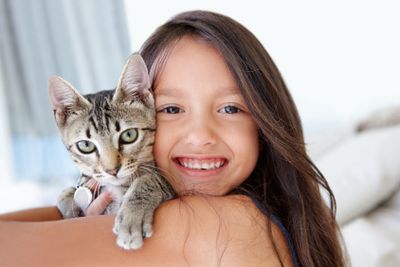 Smile, cat and portrait of child at her home cuddling,...