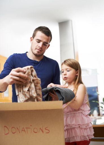 Parent, child and box with clothes for donation, promote...