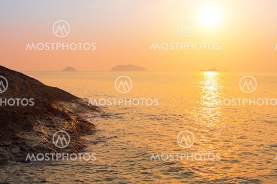 Rocky sea shore against the setting sun.