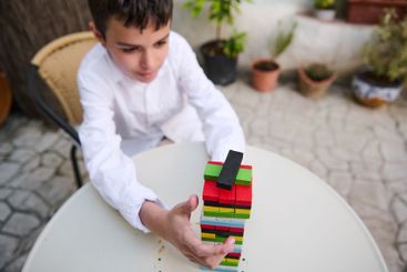 Young boy concentrating on stacking colorful wooden...