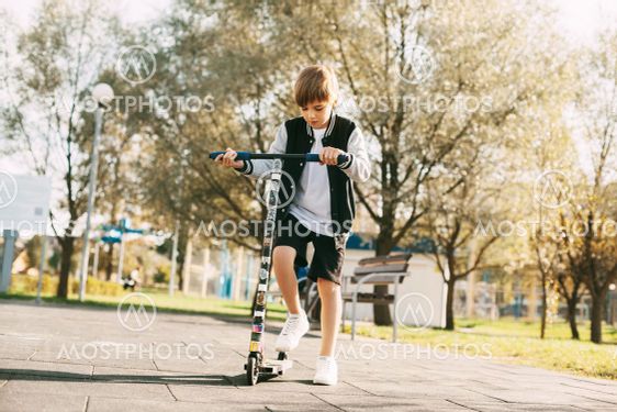 A beautiful boy rides a scooter in the Park. The child...