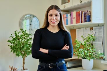 Confident young woman with crossed arms in home interior