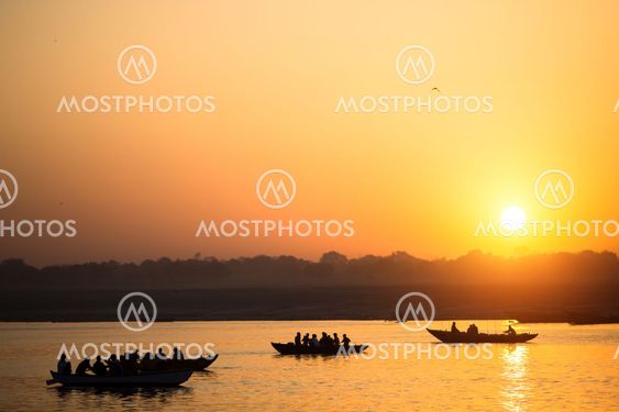Boat silhouettes with pilgrims during amazing sunset on the Holy Ganges river, Varanasi, India.