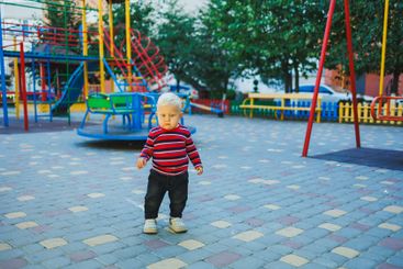 A fair-haired one-year-old boy in jeans and sneakers...