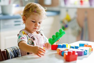 Adorable toddler girl with educational toys in nursery...