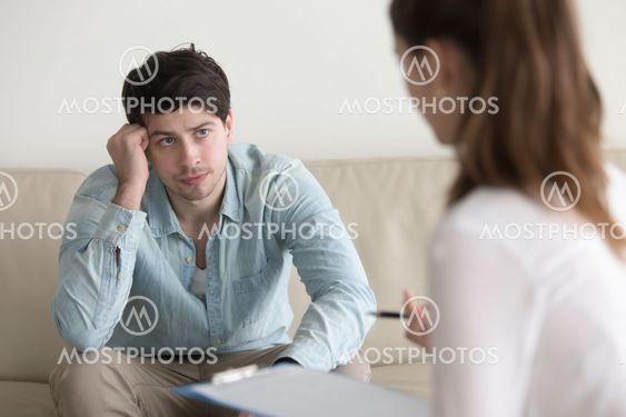 Serious guy listening to female psychologue, diagnosis or doctor