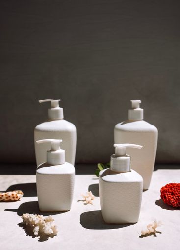 Close-up of white ceramic jars with cream or soap on a...