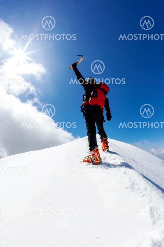 climber reaches the summit of a snowy mountain in winter