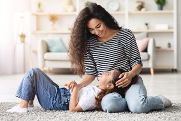 Beautiful young mother cuddling with little daughter at...