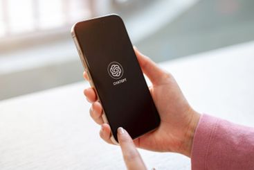 A close-up of a woman sits indoors, using ChatGPT...