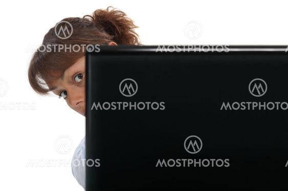 Woman peering around her laptop