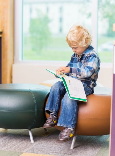 Cute Boy Reading Book In School Library