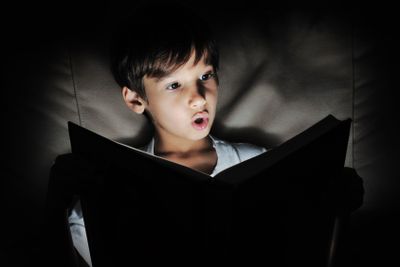 Kid reading book, light in darkness