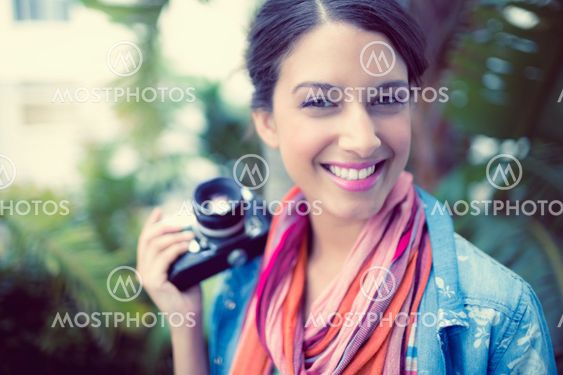Cheerful brunette photographer standing outside smiling at camera