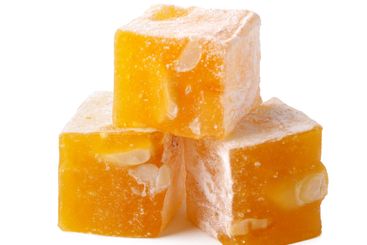 Delicious yellow candy squares with nuts stacked on a...