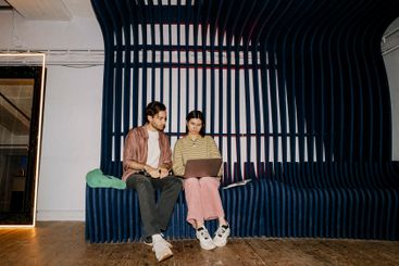 Male and female business professionals using laptop while...