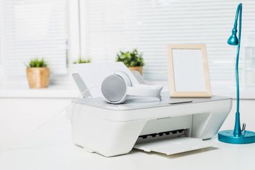 Home office setup featuring a printer, headphones, lamp,...