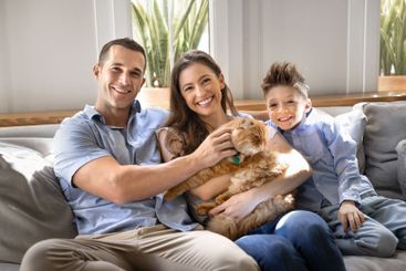 Cheerful young parents and cute son kid holding orange cat