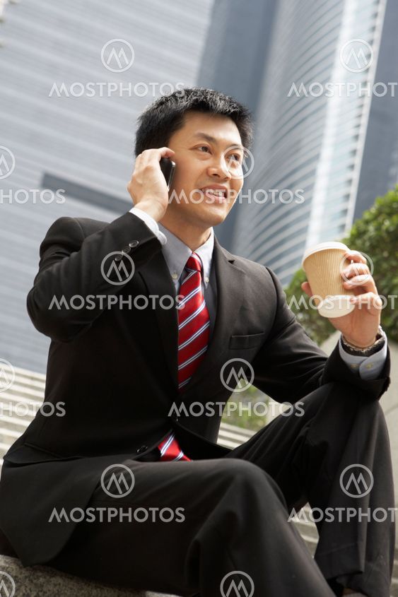 Chinese Businessman Talking On Mobile Phone With Takeaway Coffee