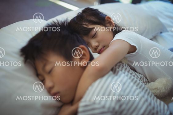 Siblings sleeping on bed in the bed room