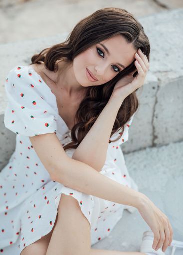 Beautiful brunette woman in summer dress sitting on...