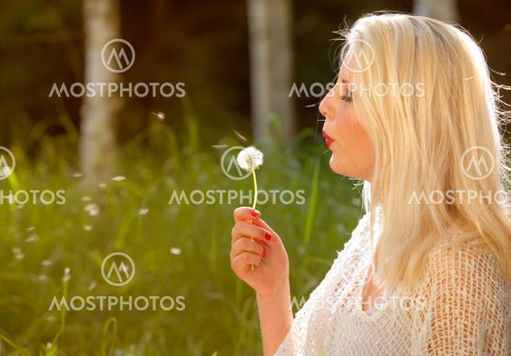 Young woman blowing dandelion