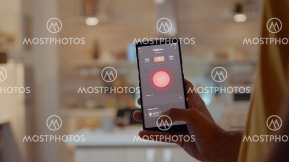 Man using smart home app touching screen to turn on...