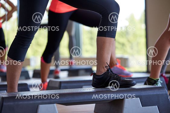 close up of women exercising with steppers in gym