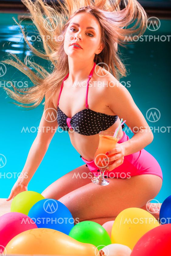 Happy woman with balloons and cocktail at poolside