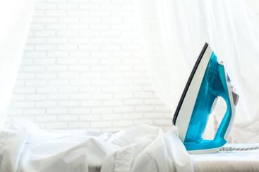 Iron on ironing board on light home interior background