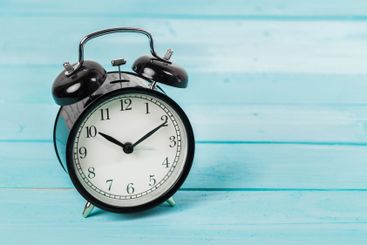 Black vintage alarm clock on wooden table