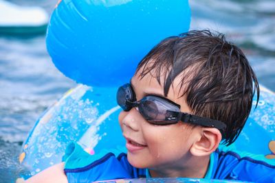 Close up funny asian boy with swim tube in pool. Outdoor. 