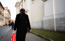 Person walking along a historic city street carrying a...