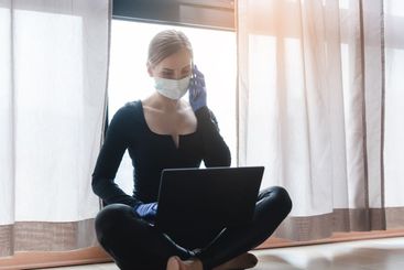 Woman in corona quarantine with phone and laptop